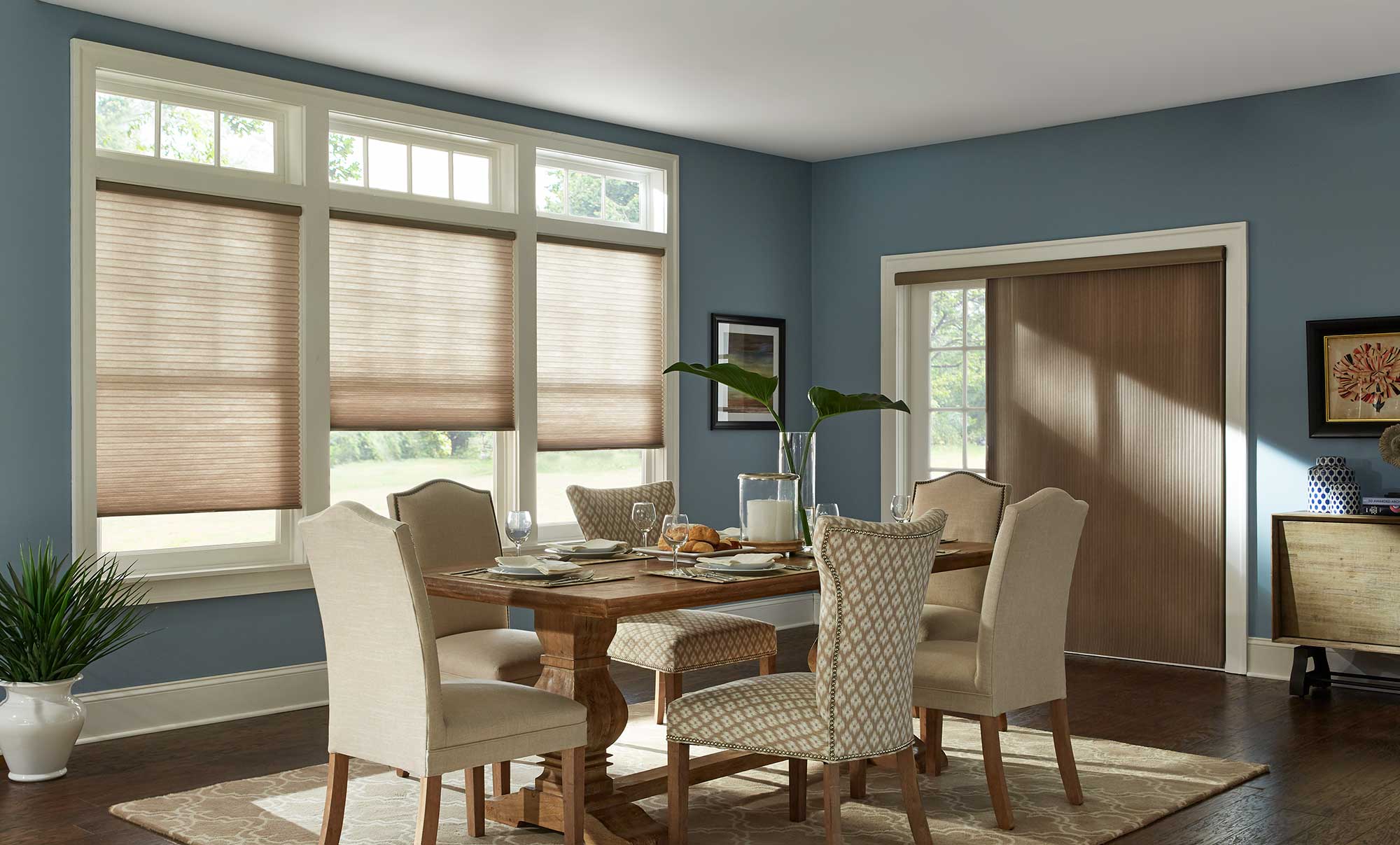Honey comb shades cover the dining room windows of a modern blue room