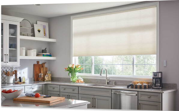 A modern kitchen with light coming through the window partially covered by new blinds