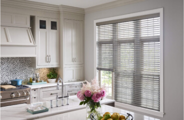 Wood blinds over windows lighting a white kitchen