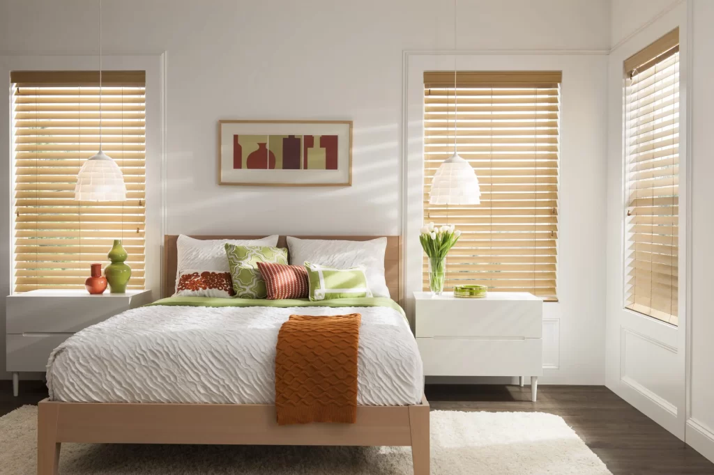 Wood blinds cover windows of a bright bedroom