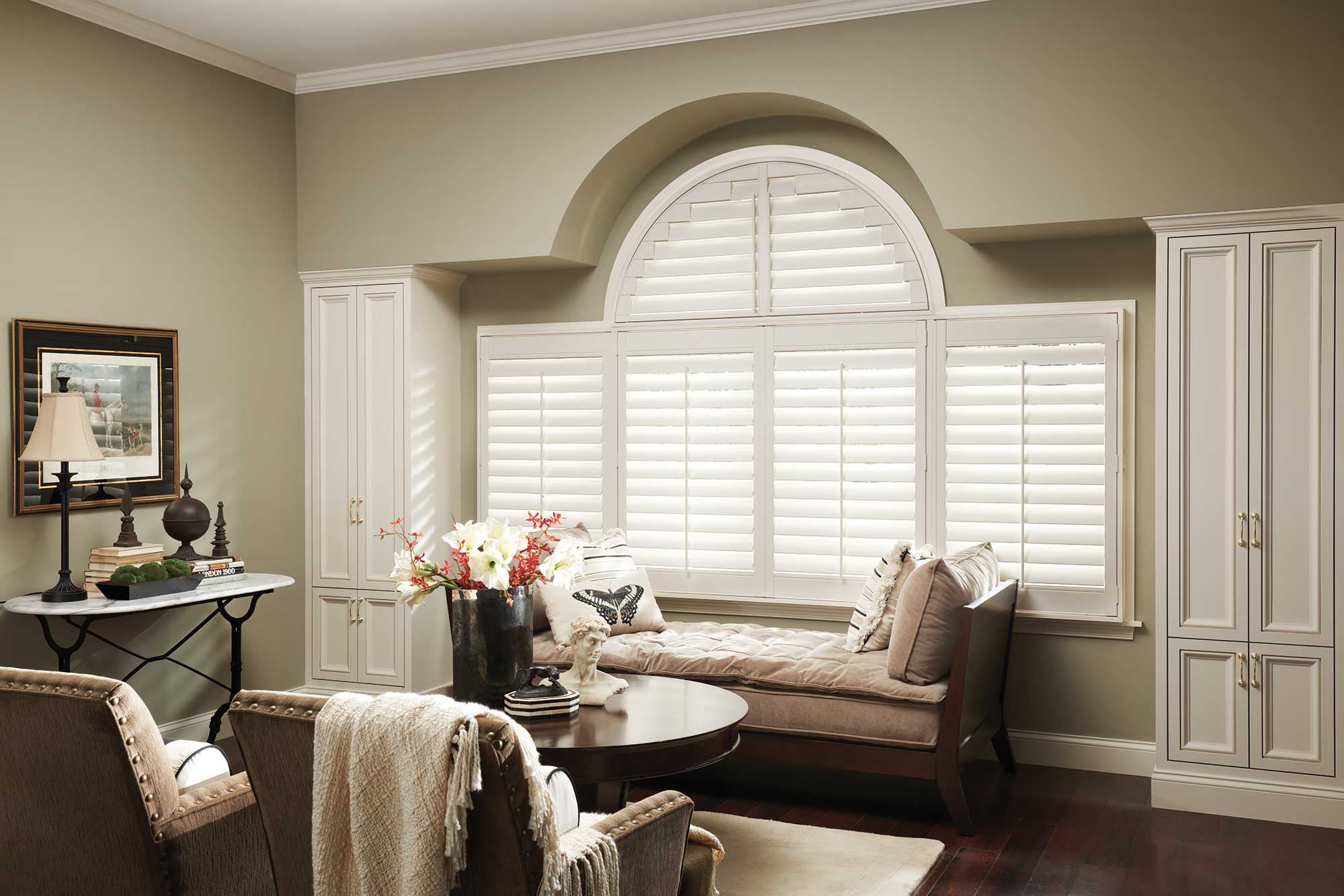 Neutral tone room with a big picture window with white wooden blinds letting in some natural light to fill the space