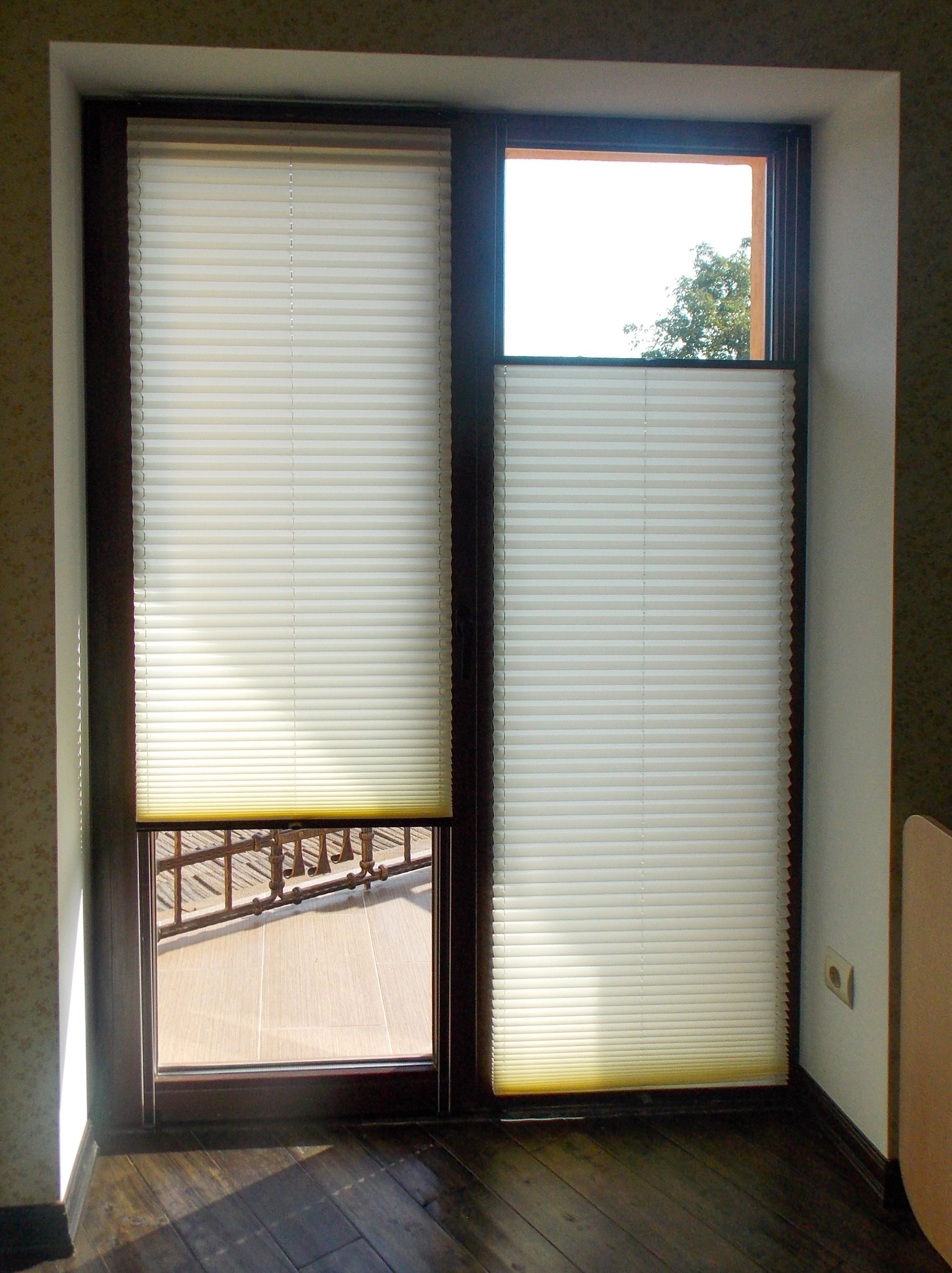 Two vertical windows covered by honey comb shades. The left window has a gap at the bottom and the right window has a gap at the top showing some custom lift options.
